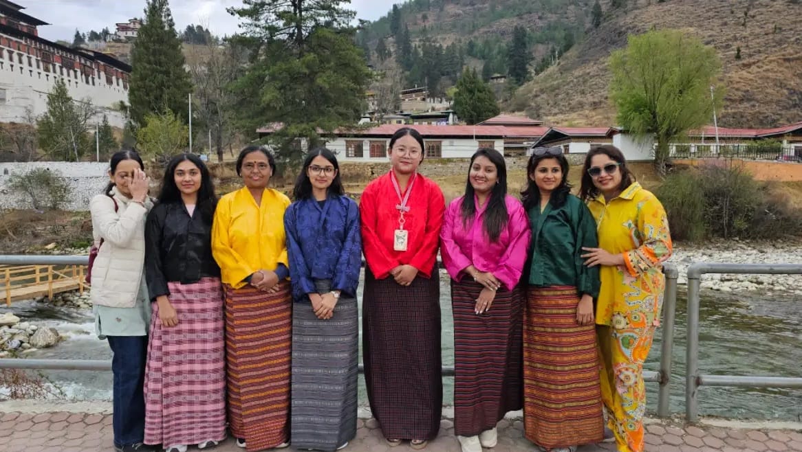Group of women posing in traditional Bhutanese clothing beside a river in Bhutan.