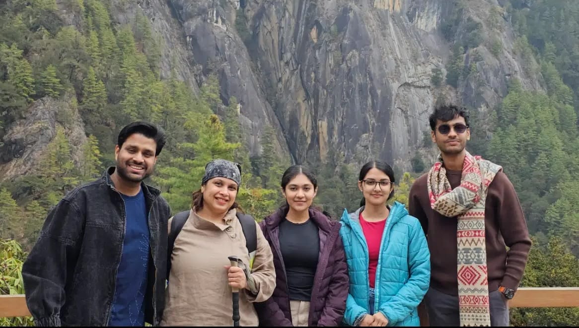 Group of travellers posing in front of rocky mountains and forest views in Bhutan.