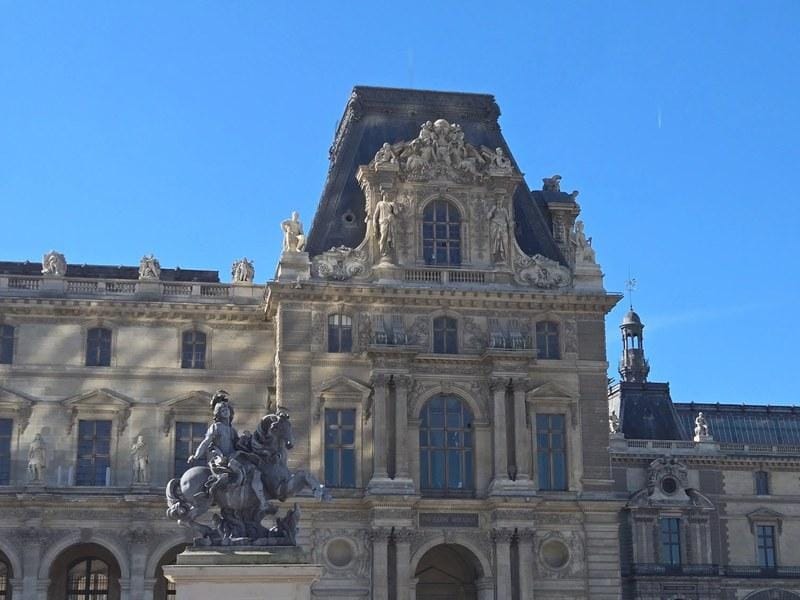 Louvre Museum Paris courtyard wide view with visitors and the glass pyramid The Louvre courtyard, Paris. April 2025.